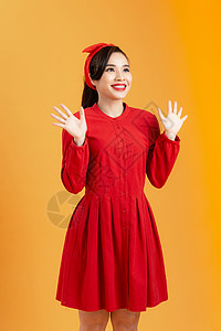 穿着红衣的亚洲快乐女人 站在橙色背景上站得特别令人惊讶红色棕色女孩微笑女士裙子女性背景图片