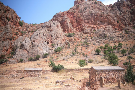 荒村该村在悬崖背景上被废弃的历史石屋 贝吉沙地颜色; 山丘背景