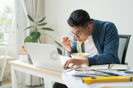 富足的工程师 甜点坐在电脑监视器前 吃面面吃面工作职场办公室男性电脑成人职业技术工人设计师背景图片