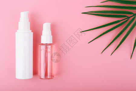 平铺在粉红背景 棕榈叶和复制空间的一套美容产品上背景图片