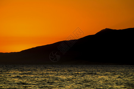 尔加基日落时山和橙色天空的海景卡波海洋山脉海滩太阳热带公园海浪地平线橙子背景