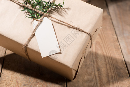 圣诞节小标签纸箱和木本上的绿色叶子空白盒子礼物细绳棕色标签白色卡片包装惊喜背景