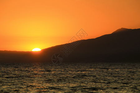 日落时山和橙色天空的海景橙子海岸线卡波海洋海滩幸福山脉海岸日落海浪背景图片