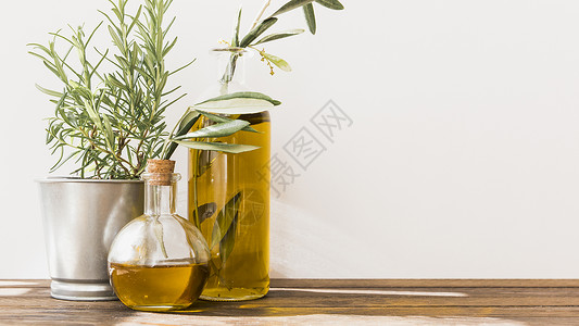 配有橄榄油瓶子的加锅迷迭香水 木制桌高清图片