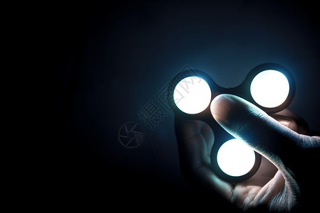 三叶指尖陀螺带霓虹灯的指尖陀螺玩具由金属或塑料制成的滚珠轴承组成 可帮助难以集中注意力的人缓解紧张的能量或心理压力 选择性焦点背景