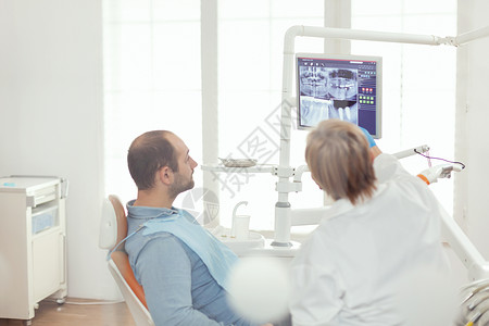 坐在牙椅上看牙齿射线摄影的病男高清图片