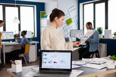创办公司办公室的企业女商务人士阅读统计数据; 在开办公司办事处背景图片