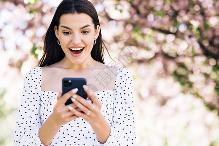 特写快乐的女孩在电话上阅读好消息 惊讶的女士在电话上庆祝胜利 幸福女人的肖像在手机上享受成功博主视角微笑商业员工博客垂直讯息技术背景图片