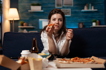 披萨盒子女人的肖像 看着喜喜剧电影 吃着美味的送货 披萨切片 在沙发上放松啤酒消费者客厅午餐筷子食物面条命令垃圾长椅背景