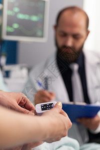 冰沁活氧面膜贴Asisstant护士将医疗血氧计贴在手指上 而医生男子则写心跳脉搏率背景