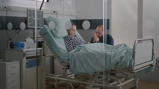 之感病率在医院病房中 生病的女病人在担心父亲为恢复病情而祈祷时睡觉背景