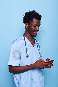 美国护士做护士的人看着智能手机 笑着微笑保健药品从业者快乐成人专家卫生诊所男人擦洗背景