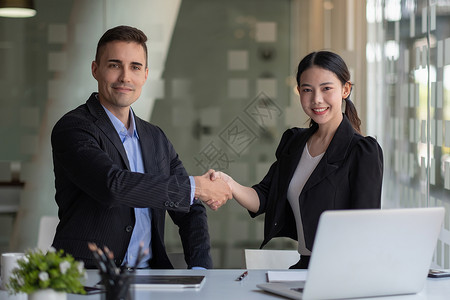 快乐的白人男性和亚洲女性握手 成功的商务人士握手后对两家公司来说都是很好的交易 企业并购理念背景图片
