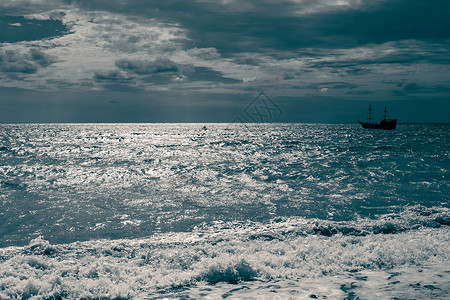 海景 一艘帆船在黑暗的天空和戏剧性大气的背景下航行于海洋中 深蓝向上飞去背景图片