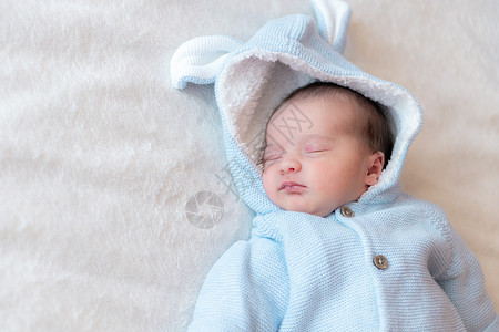 第一文字素材新生儿特写 文字位置 新生儿穿着蓝色衬衫仰卧在白色背景的顶视图上睡觉 米色背景下熟睡的新生婴儿的画像背景