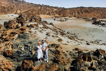 微微别霍一个穿着白色衣服和眼镜的男人和一个女孩站在泰德火山的火山口 一对夫妇站在西班牙特内里费岛火山口的一座山上世界公园慢跑者沙漠石头假背景