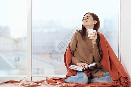 女人在窗台上喝着一杯酒 在清晨读一本书思维杯子闲暇女孩假期咖啡女士女性格子背景图片
