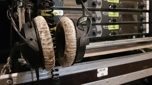 在音乐会场或电视节目后台的音响工程师设备中的耳机中使用耳机背景