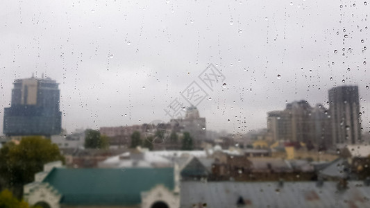 在多云的天气里 秋天的城市背景上滴着湿窗户 雨中窗外景色 雨中玻璃窗上的水滴 城市场景背景模糊戏剧性秋雨反射液体房子风暴气泡季节背景图片