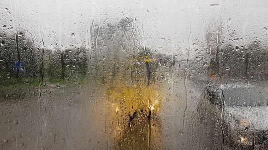 后退键秋天汽车后窗下雨 从雨滴的汽车透过窗户 可以看到城市中行驶的汽车的道路内部视图 在后窗的视野中驾驶汽车斑点风暴反射速度运动车辆交背景