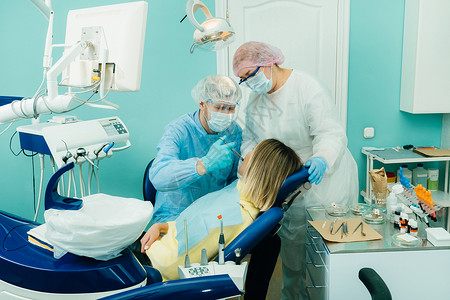 名族乐器一名牙医 在牙科办公室与一名助理一起使用保护面罩口罩科内炎止痛药临床治疗病人男人访问微笑女士医生防护空腔背景