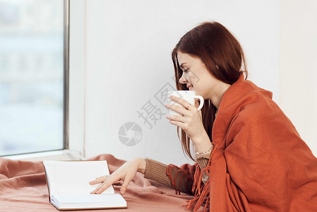 女人在窗台上喝着一杯酒 在清晨读一本书思维女士闲暇咖啡格子女孩女性假期杯子背景图片
