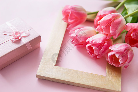 粉色花朵框架粉红色和黄色的郁金香花 礼品盒排列在粉红色的背景上 从顶部的视图 春天的概念 妇女节 母亲节背景