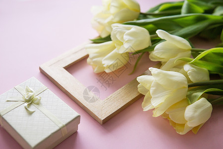 黄色礼物盒黄色郁金香花 照片框和礼品盒以粉红色背景排列 从上到下 光滑的景色;春天的概念;妇女节背景