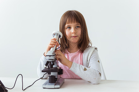 以数字显微镜做功课的可爱小孩的肖像 技术 科学和儿童概念 笑声金发测量实验室生物知识管子微生物学童年学校生物学背景图片