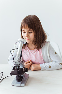 以数字显微镜做功课的可爱小孩的肖像 技术 科学和儿童概念 笑声女孩学生教育测量微生物学实验室科学家班级知识金发背景图片
