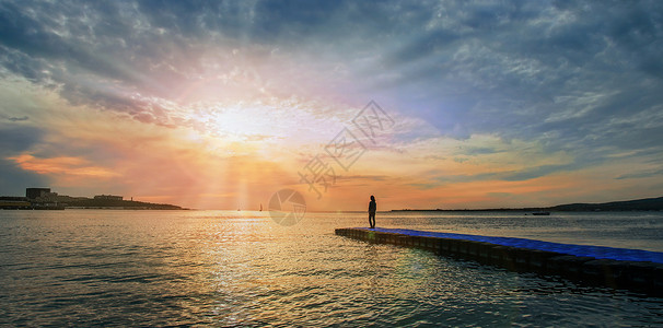 日落时 女人站在海边码头上高清图片