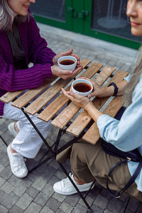 年长的高级女士老朋友在户外咖啡厅露台的小桌边端着咖啡杯 坐在小桌子上背景图片