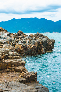 美丽全景纯蓝色 lazure 空海天际线 生动的棕色灰色岩石破旧的悬崖 水花 积云天空 山岛背景 大流行后的概念海上旅游 自然的背景图片