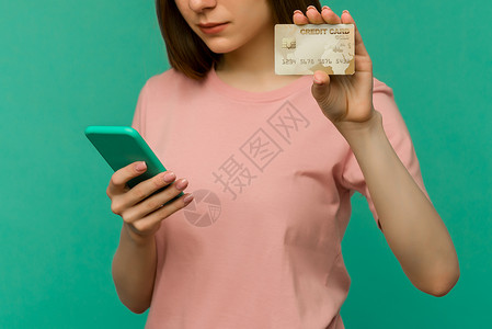 使用持有信用卡的手机 将蓝墙背景与世隔绝 校对工作室信用卡成人信用微笑电话商业银行细胞惊喜背景图片