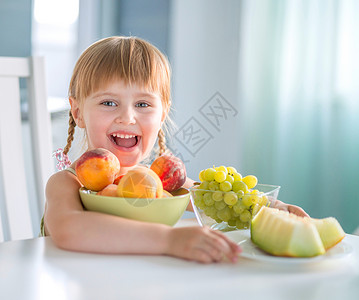 小女孩挑瓜带着桃子 葡萄和西瓜在桌边笑着的小女孩食物童年微笑孩子幸福桌子婴儿盘子女性水果背景