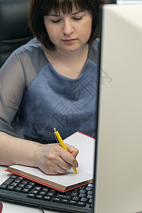 年轻女性在工作场所用笔记本写作 工作秘籍 任务经理 日程安排任务背景图片