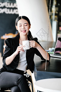 一名女性营销经理在返回工作岗位减少沉睡之前 正在用一杯咖啡来休息 笑声商务人士女士职业活动办公室快乐技术棕色享受背景图片