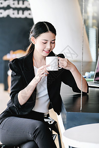 一名女性营销经理在返回工作岗位减少沉睡之前 正在用一杯咖啡来休息 笑声商务手机摄影幸福休闲棕色商业咖啡店女士享受背景图片
