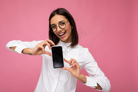 三品一标美丽微笑的年轻女性漂亮的照片穿着休闲时尚的服装站在孤立的背景与复制空间拿着智能手机显示手机在手与空屏幕显示用于模型看相机幸福横幅背景