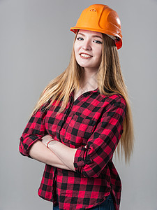 橙色格子一个年轻有魅力的女人的肖像 头戴橙色头盔金发 穿着中性灰色背景的金发工程商业橙子格子女孩金发女郎工作职业建筑学微笑背景