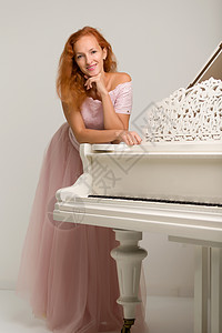 美丽的年轻女子 在白色大钢琴附近琴键手指音乐家艺术家奢华旋律古典音乐音乐音乐会学习背景图片