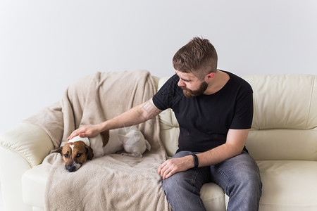 沙什利克睡沙发上有可爱的狗杰克·罗瑟利帽的男人 宠物和家喻户晓背景