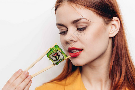 开心的红头发女人 筷子寿司日本菜摄影服务女性舌头食物正方形海鲜美丽工作室黄瓜背景图片