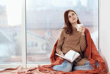 女人在窗台上喝着一杯酒 在清晨读一本书咖啡女孩格子女士思维杯子假期闲暇女性背景图片