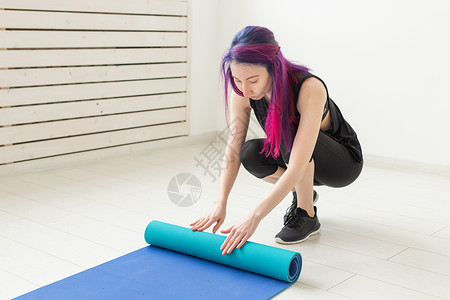 蓝色头发女孩穿着彩色头发折叠体操垫和体育课课后运动垫的苗条女孩 瑜伽和小便的概念耐力活力健身房训练练习护理教练运动蓝色成人背景