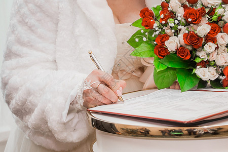 婚礼签名新娘的手在婚礼结束时将双方同意结婚的签名笔印合同家庭订婚妻子文档写作裙子女士桌子庆典背景