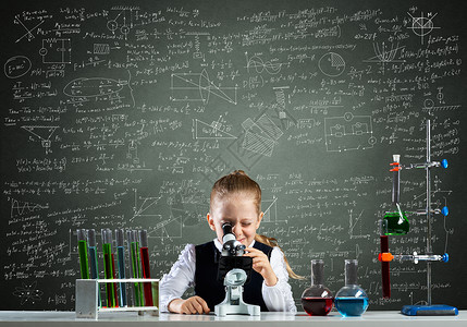 透过显微镜观察的小女孩科学科学家烧瓶技术公式数学童年教育实验化学品学校生物学背景图片