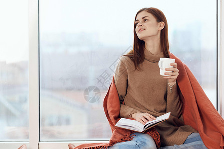 女人在窗台上喝着一杯酒 在清晨读一本书闲暇女性假期杯子女士女孩格子思维咖啡背景图片