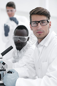 坐在桌子上认真的科学家们 坐在这里生物管子显微镜检查健康生物学实验卫生蓝图男性背景图片
