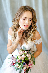 年轻迷人的新娘在摄影工作室穿着白礼服和花束背景图片